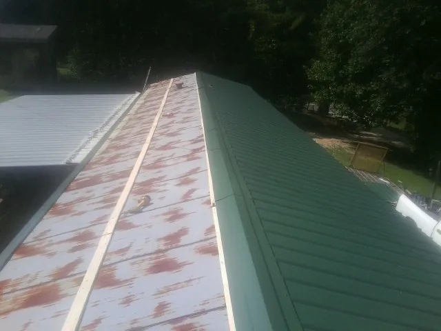 Old rusted panels beside newly installed green metal roofing — Wind Damage Roof Repair by Roofing Brothers in Lancaster