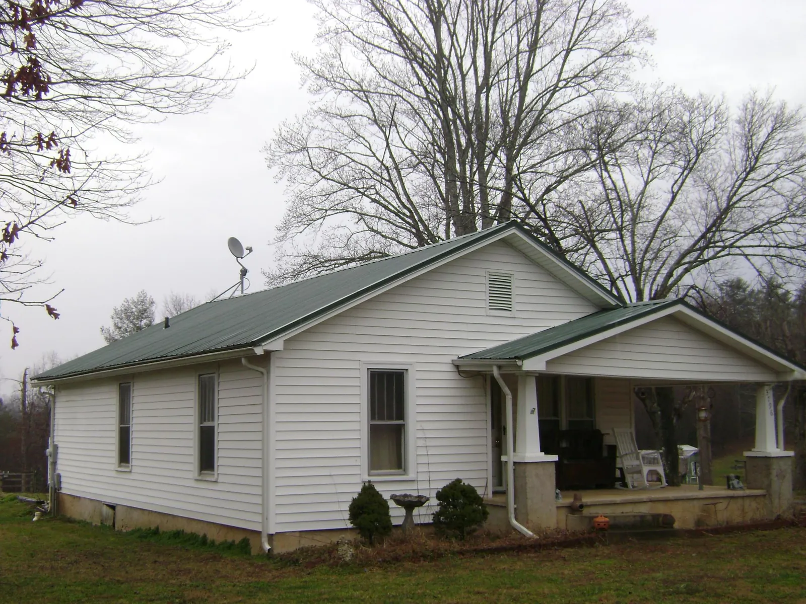 Green metal roof on a white bungalow with a side porch in Lancaster