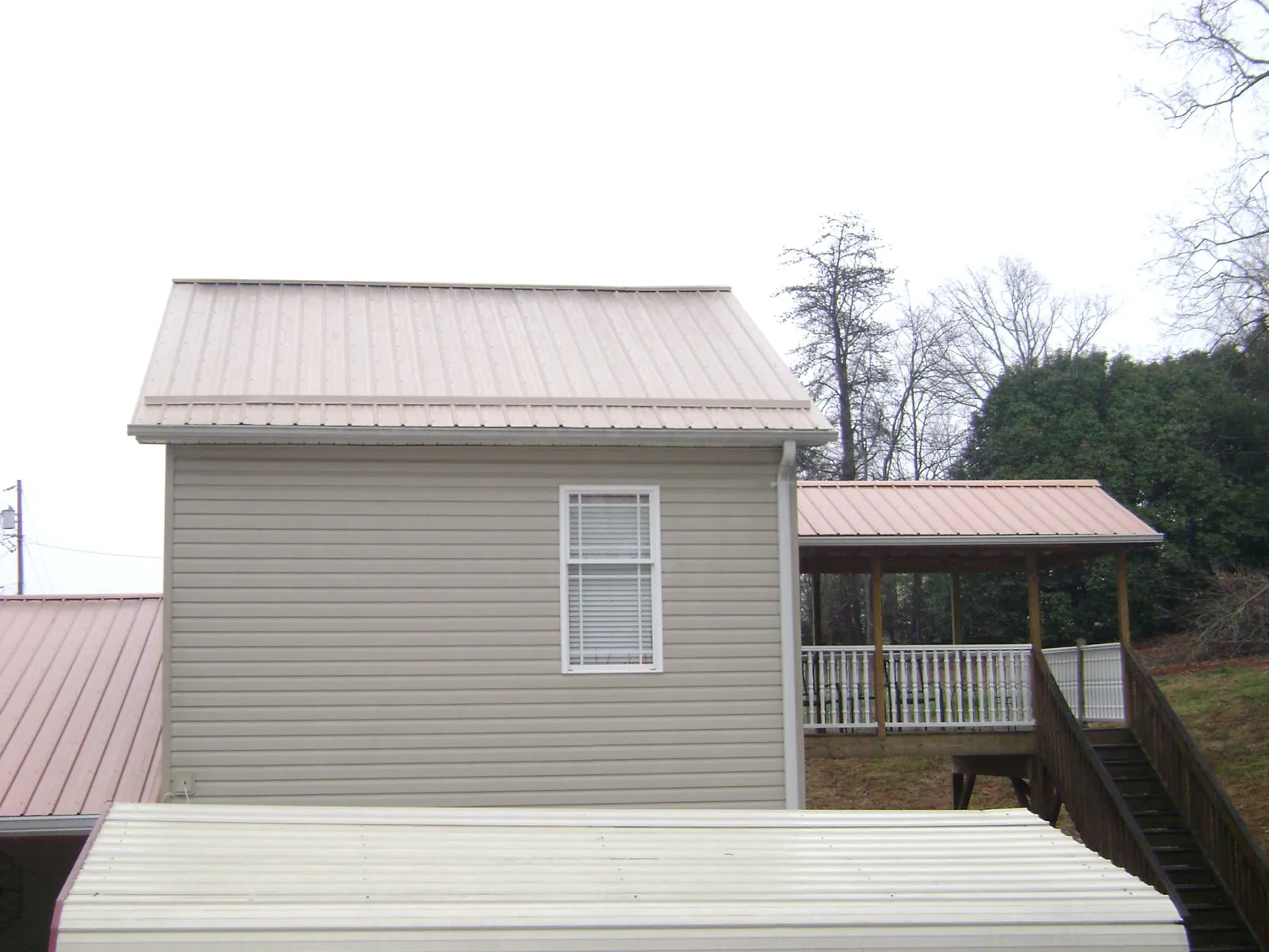 Tan metal roofs on a two story addition and attached porch, from a Roof Replacement job in Lancaster